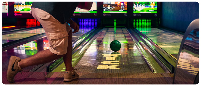 Uma pessoa que acaba de lançar uma bola de boliche na pista para derrubar apenas um pino.