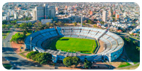 Vista aérea de um grande estádio de futebol cercado por uma cidade densamente povoada.