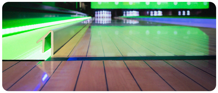 Imagem de uma canaleta com LED verde na parte de trás e ao fundo o final da pista de boliche.