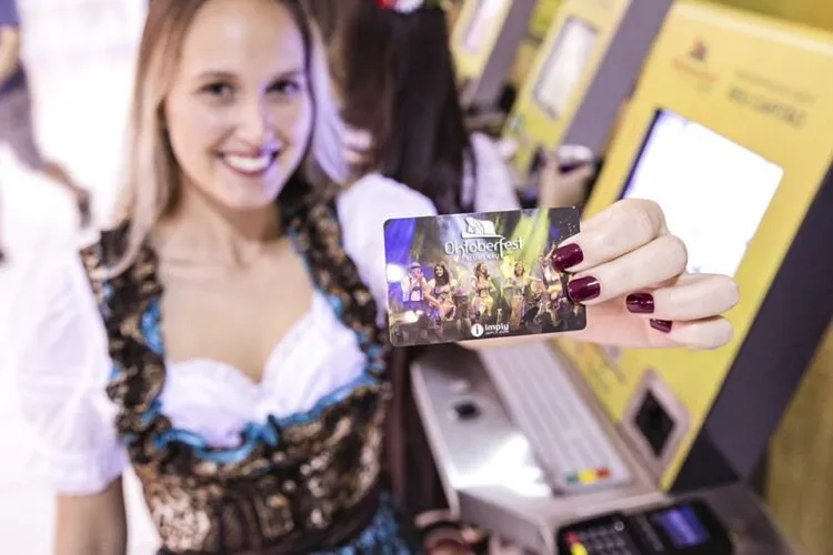 Mulher vestida de roupa típica segurando cartão da Oktoberfest