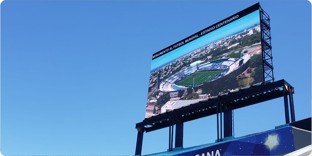 Painel LED comunicação visual, com a imagem de um estádio com vista aérea e a frase: "Monumento al fùtebol mundial - estadio centenario".