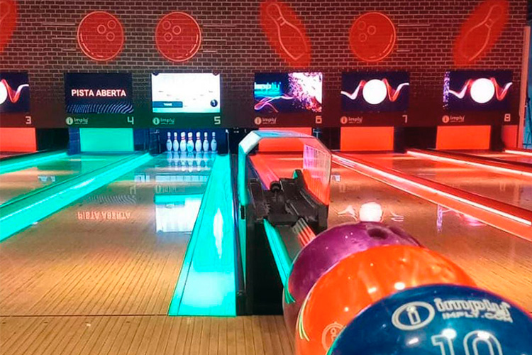 Visão das pistas do estabelecimento com os pinos posicionados e as bolas alinhadas no suporte para inicio do jogo.