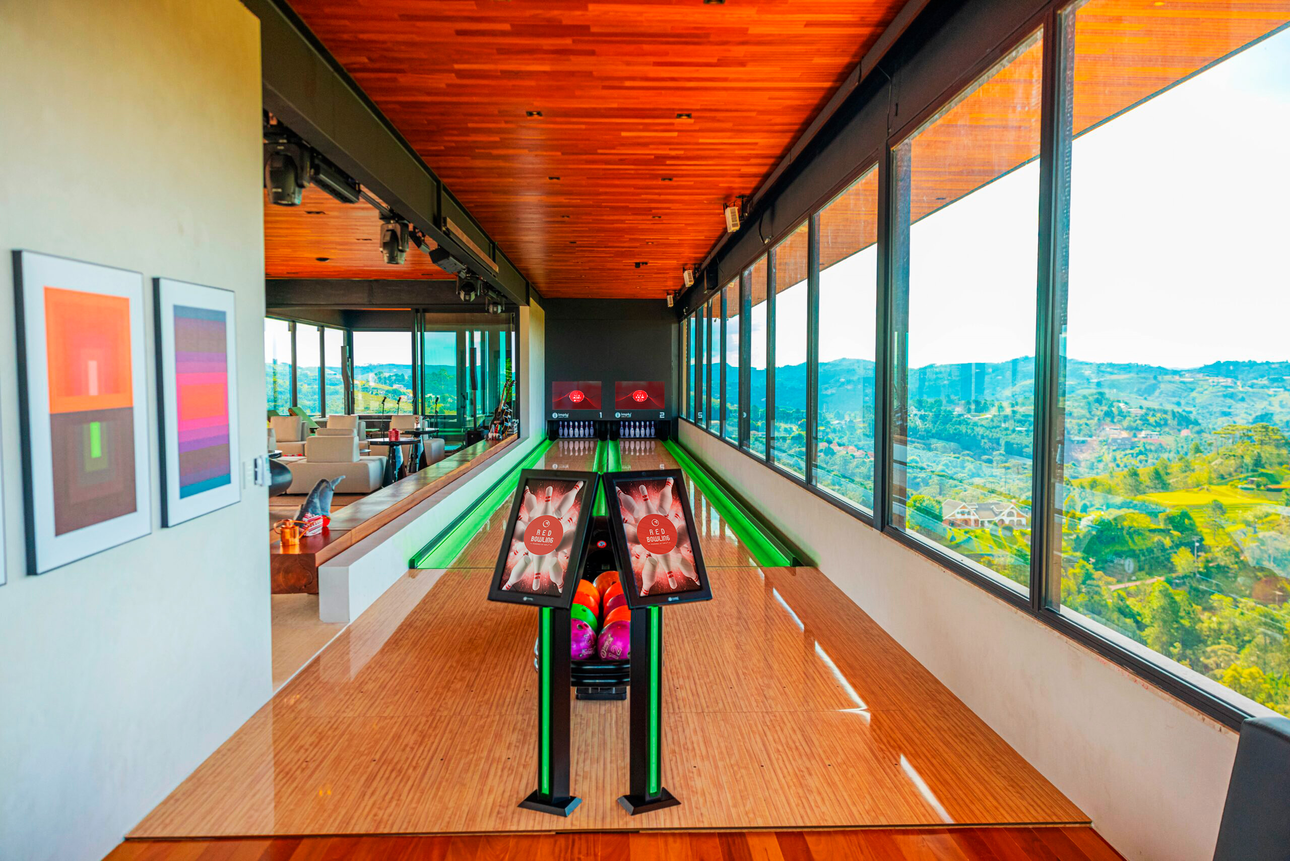 Pista de boliche residencial em uma casa, a direita a vista da paisagem para fora casa, e a esquerda a continuação da casa.